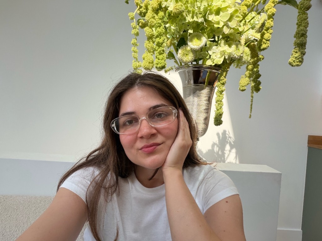Aina, founder of Flower Enthusiast, beside a cascading green arrangement